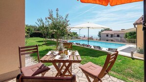 Une terrasse avec une piscine, des sièges extérieurs et une vue sur l’espace piscine.