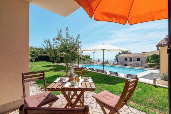 Une terrasse avec une piscine, des sièges extérieurs et une vue sur l’espace piscine.