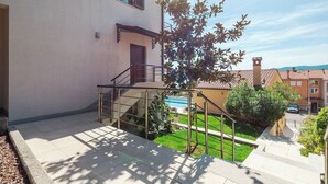 A residential building with a staircase leading to a balcony, a small garden area, and a visible swimming pool in the background. - RED - E&T apartments with a beautiful pool (Rabac)