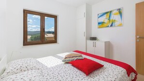 A bedroom with a bed, a window with a view, a cabinet, and a painting on the wall. - RED - E&T apartments with a beautiful pool (Rabac)