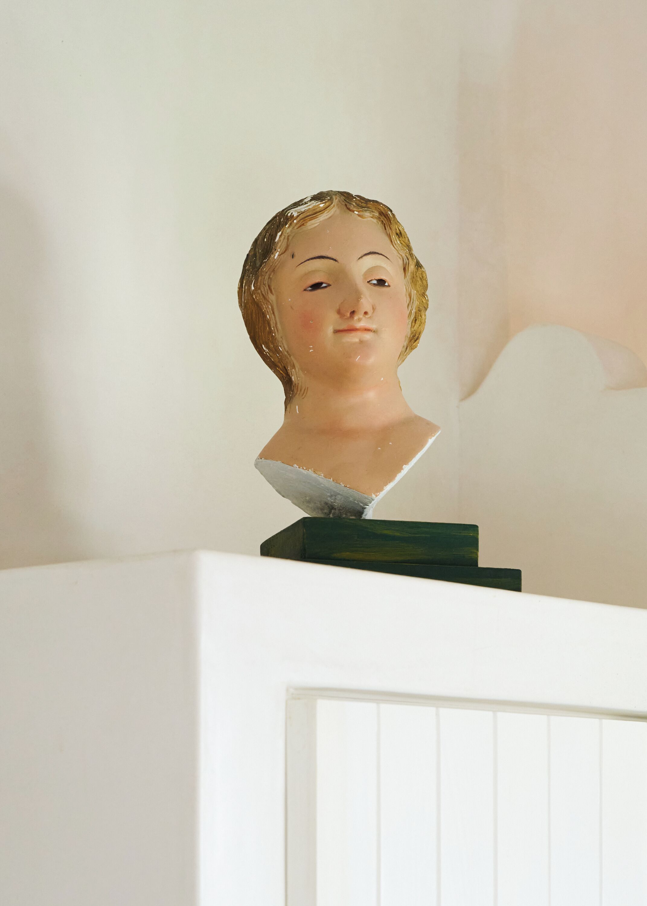 A bust sculpture on a pedestal against a plain wall.