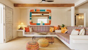 A living room with a sofa, ottomans, a coffee table, and a ceiling fan. - Casablanca Beachfront Gateway (Troncones)