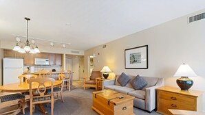 A modern living room with a sofa, coffee table, and dining area. - Resort Style w/ Balcony, Hot Tub and Full Kitchen (Shanty Bay)
