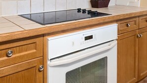 A kitchen with wooden cabinets, a white microwave, a stove, and a built-in oven. - Resort Style w/ Balcony, Hot Tub and Full Kitchen (Shanty Bay)