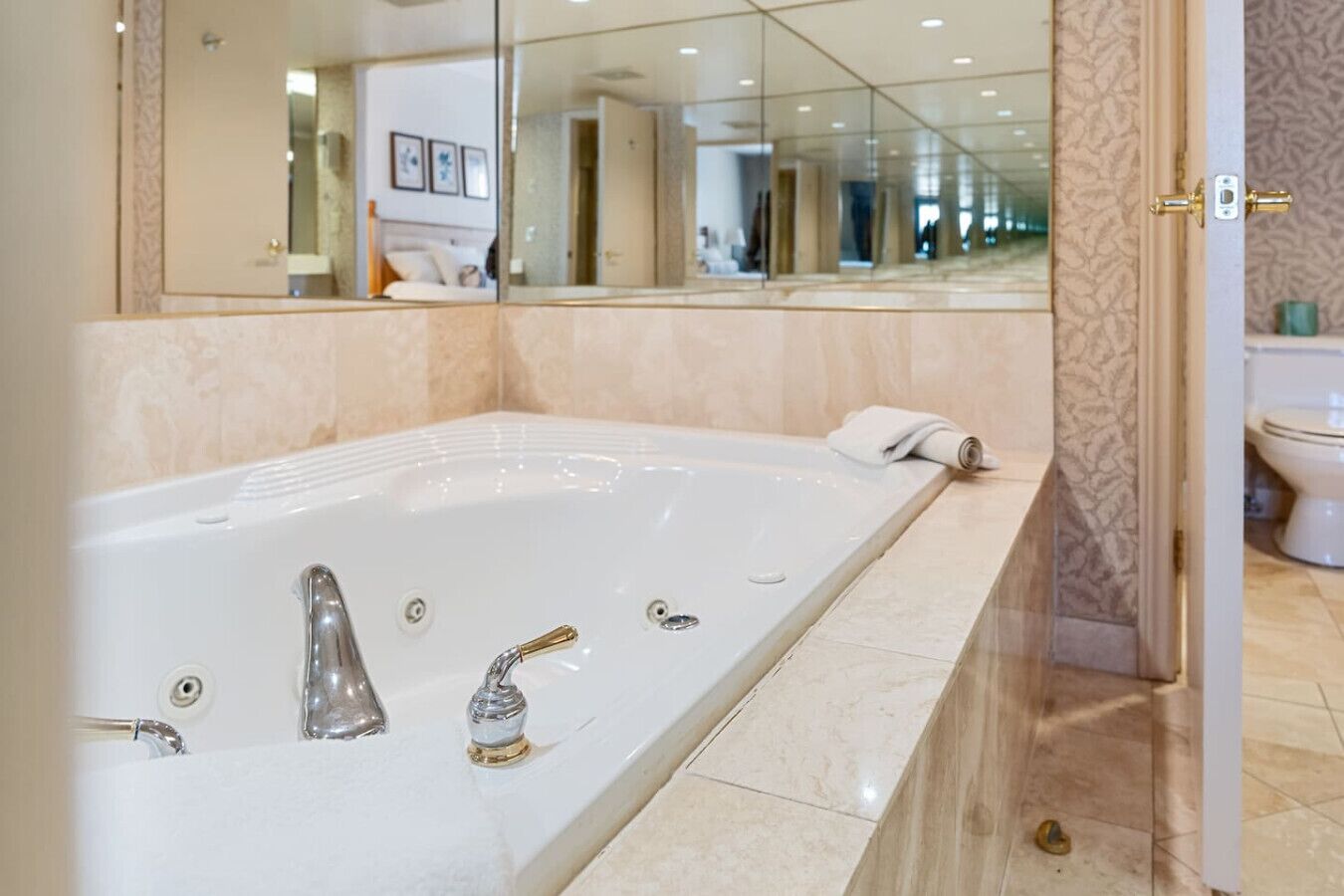 A modern bathroom with a large bathtub, a sink with two faucets, and a toilet.