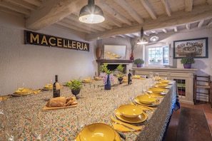 A dining table set with yellow plates, glasses, and a bottle, with a sign reading 'MACELLERIA' on the wall. - Country House Casalguidi 191 Private Pool (Serravalle Pistoiese)