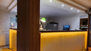 Un'area reception con una scrivania in legno, un banco accettazione e una reception con un monitor computer.