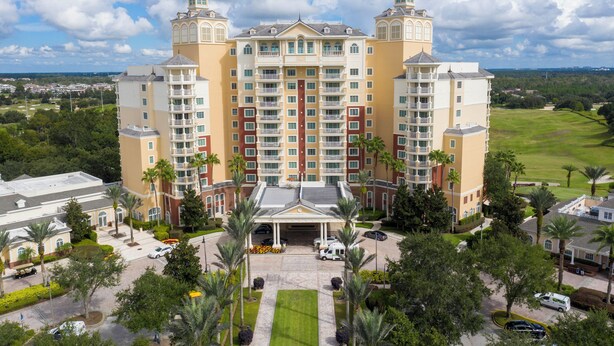 A multi-story hotel with a central entrance, surrounded by palm trees and a well-maintained lawn. - Stunning 3 Bed Apartment - Reunion Resort (Kissimmee)