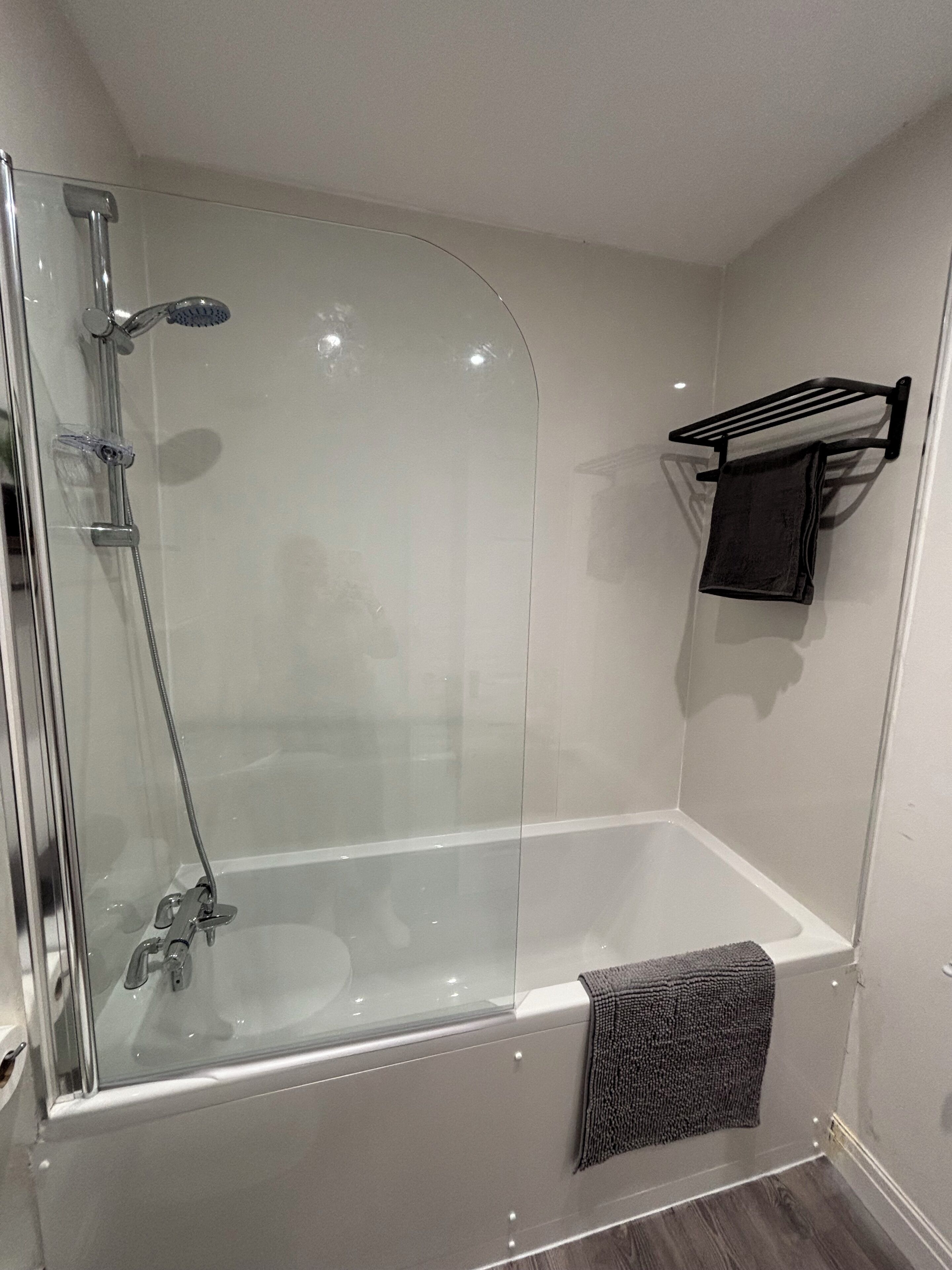 A modern bathroom with a glass-enclosed shower, a bathtub, and a towel rack.