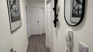 A hallway with framed artwork, a wall-mounted phone, and a door at the end.