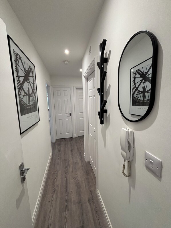 A hallway with framed artwork, a wall-mounted phone, and a door at the end.