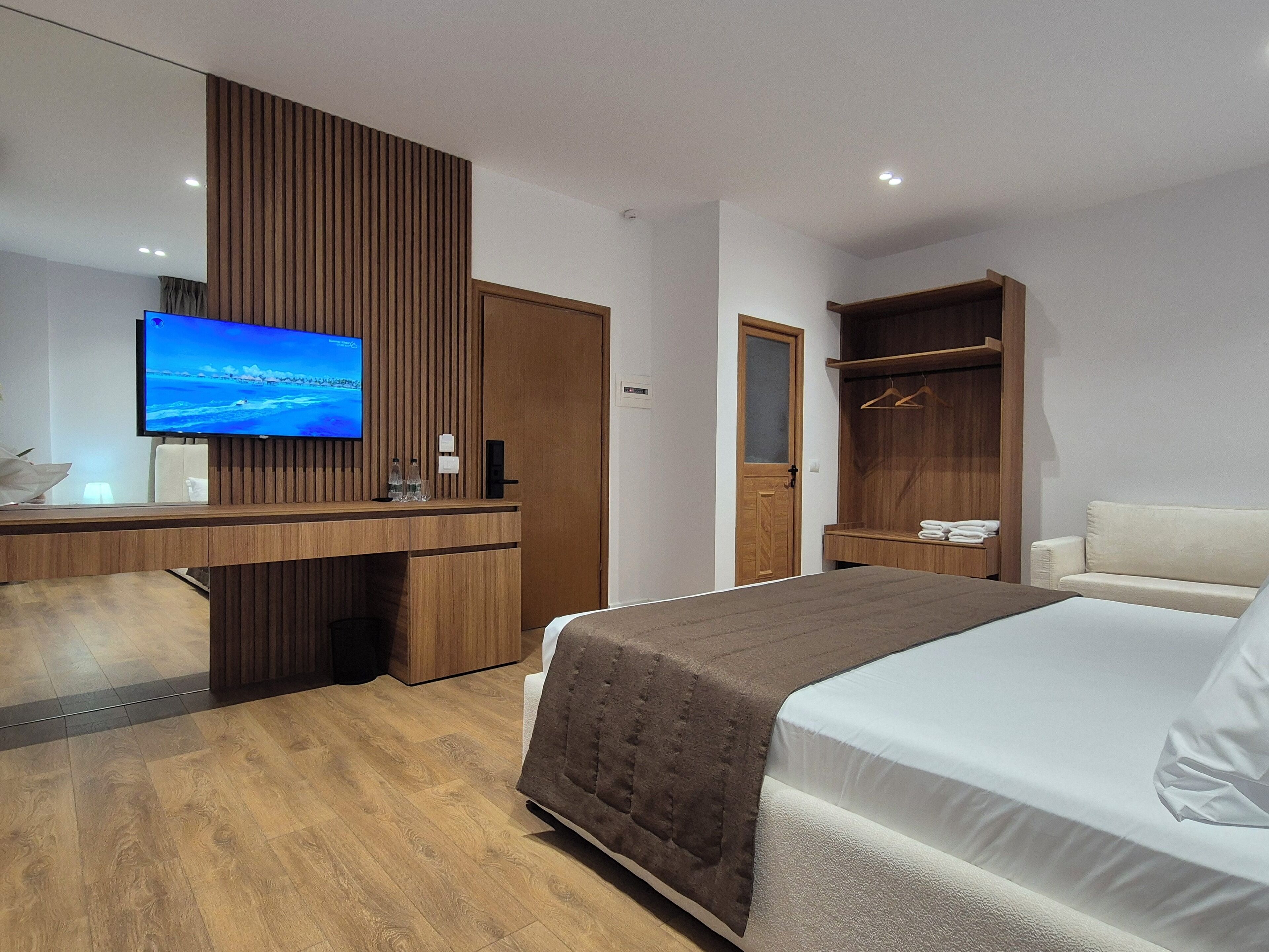 A hotel room with a bed, a desk with a TV, a wardrobe, and a bathroom.