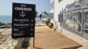 Un panneau indiquant l’hôtel Orchids, avec des flèches indiquant la direction de la réception, du restaurant, du bar et de la plage.