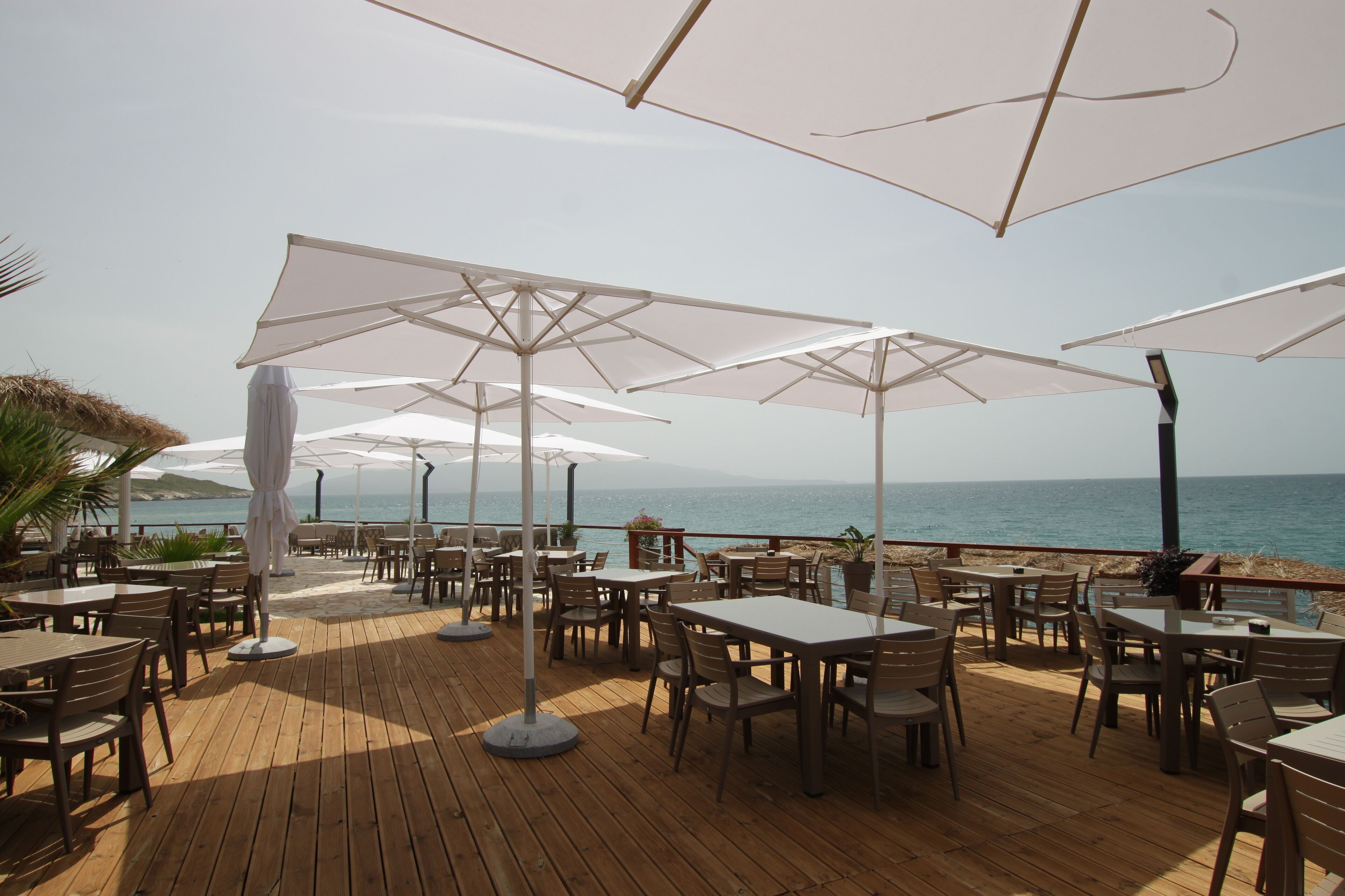 Un área de comedor al aire libre con mesas y sombrillas, con vista al mar.