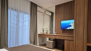 Une chambre d’hôtel moderne dotée d’un grand lit, d’un bureau en bois, d’une télévision et offrant une vue sur la mer.