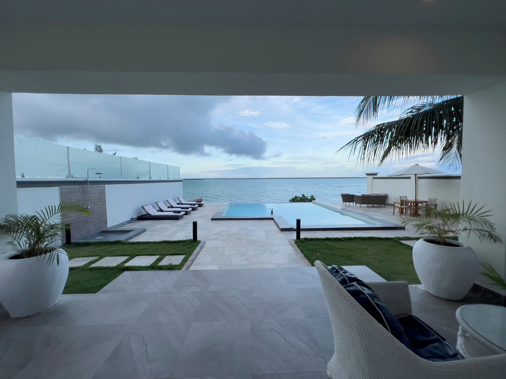 A modern outdoor pool area with lounge chairs and a view of the sea.