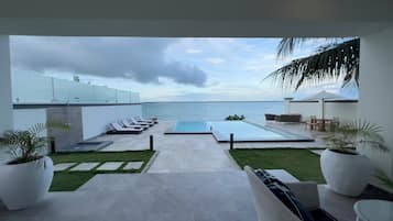 A modern outdoor pool area with lounge chairs and a view of the sea.
