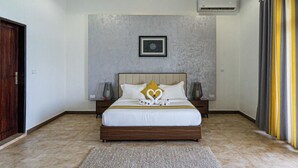 A bedroom with a bed, a nightstand, an air conditioning unit, and a wall-mounted picture. - DT Beachfront Villas (Fumba)