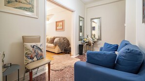 A living room with a blue sofa, a beige armchair with a zebra pillow, a small table with a bowl, and a rug. - Piraiki Sea View Apt, 2bdrms, 4 pers by MPS (Pireas)