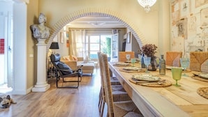 A dining area with a long wooden table set for a meal, a chandelier, and a classical bust sculpture. - Masia Las Torres by Hello Homes Sitges (Sitges)