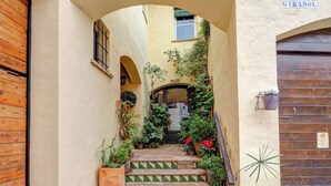 A narrow staircase with green and yellow patterned tiles, flanked by potted plants and a wooden door on the left. - Masia Las Torres by Hello Homes Sitges (Sitges)