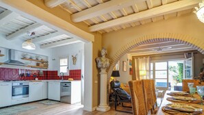 A spacious kitchen with modern appliances, a dining area with a wooden table, and a view of the outdoors. - Masia Las Torres by Hello Homes Sitges (Sitges)
