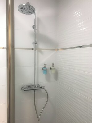 A shower with a handheld showerhead, a wall-mounted faucet, and a handheld shower hose. There are two soap dispensers on the wall. - Hostel Teracite (Varna)
