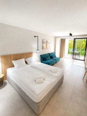 A hotel room with a large bed, a sofa, a dining table, and a balcony with a view. - Hostel Teracite (Varna)