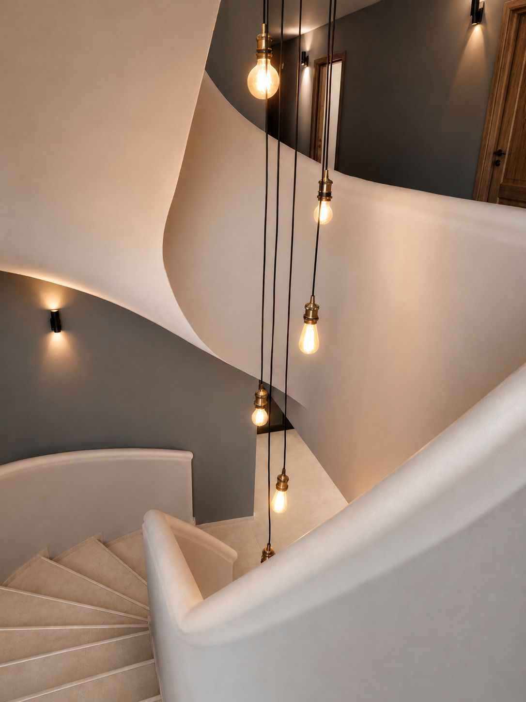 A modern staircase with a curved design, illuminated by hanging light fixtures.