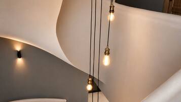 A modern staircase with a curved design, illuminated by hanging light fixtures.