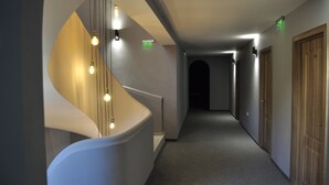 Un interior moderno con una escalera curva, un largo pasillo y puertas de madera.