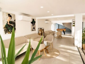 A modern living room with a sectional sofa, a glass coffee table, and a dining area with a wooden table and chairs. - Hostel Teracite (Varna)