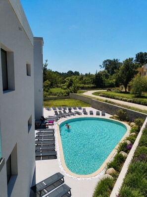 A swimming pool with lounge chairs and a landscaped garden. - Hostel Teracite (Varna)