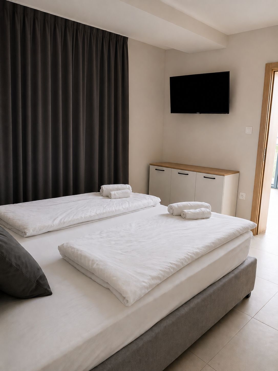 Una habitación de hotel con una cama grande, un televisor de pantalla plana montado en la pared y un armario de madera.