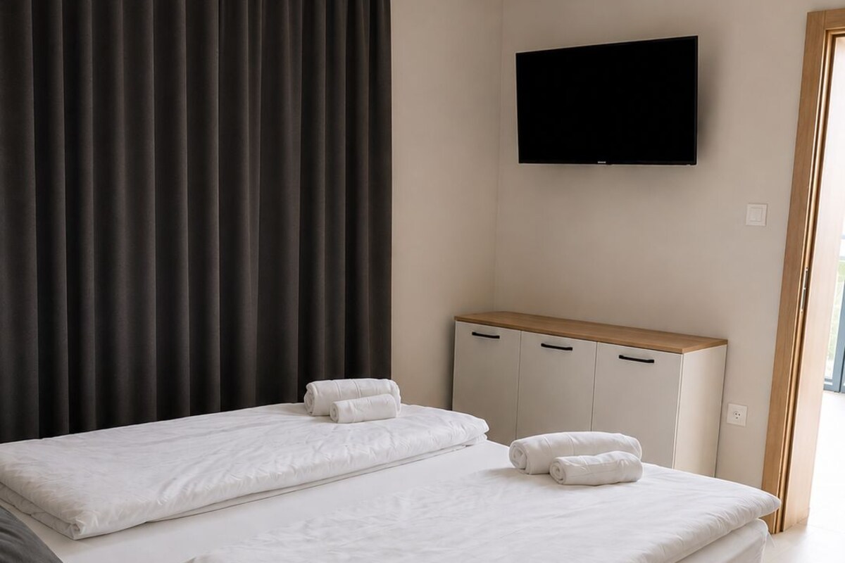 A hotel room with a large bed, a flat-screen TV mounted on the wall, and a wooden cabinet.