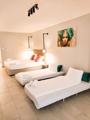 A hotel room with two beds, a sofa, and a painting on the wall. - Hostel Teracite (Varna)