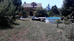 Una casa con techo de tejas, rodeada de árboles y un patio cubierto de césped.