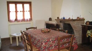 Un comedor con una mesa preparada para cuatro, una chimenea y un ventanal con cortinas.