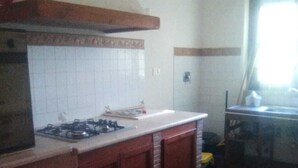 Una cocina con estufa a gas, armarios de madera y una alfombra estampada.