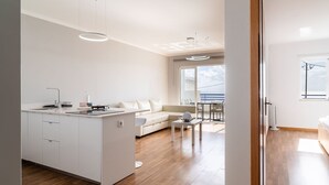 Une cuisine moderne dotée d’un îlot central, un coin repas avec une table et des chaises, un canapé et une vue sur la mer grâce à de grandes fenêtres.