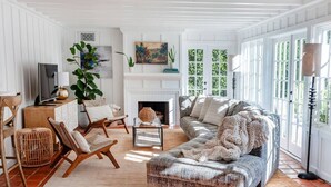 Una sala de estar con chimenea, televisión y un ventanal con vistas a zonas verdes.