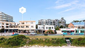A coastal town with a mix of residential and commercial buildings, including a hotel named 'BAY VILLAGE'. - Del Mar - 1 bed option (Shoal Bay)