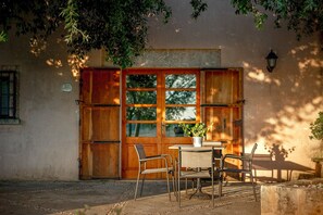 A rustic wooden door with multiple windows, a small table with chairs, and a potted plant. - Agritourism SA Franquesa Vella (Vilafranca de Bonany)