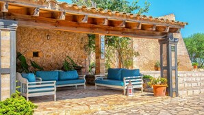 A covered outdoor seating area with stone walls and wooden furniture. - Agritourism SA Franquesa Vella (Vilafranca de Bonany)