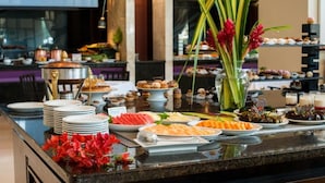 A buffet with various dishes and a decorative vase with flowers. - Hotel Hesperia de Valencia (Naguanagua)
