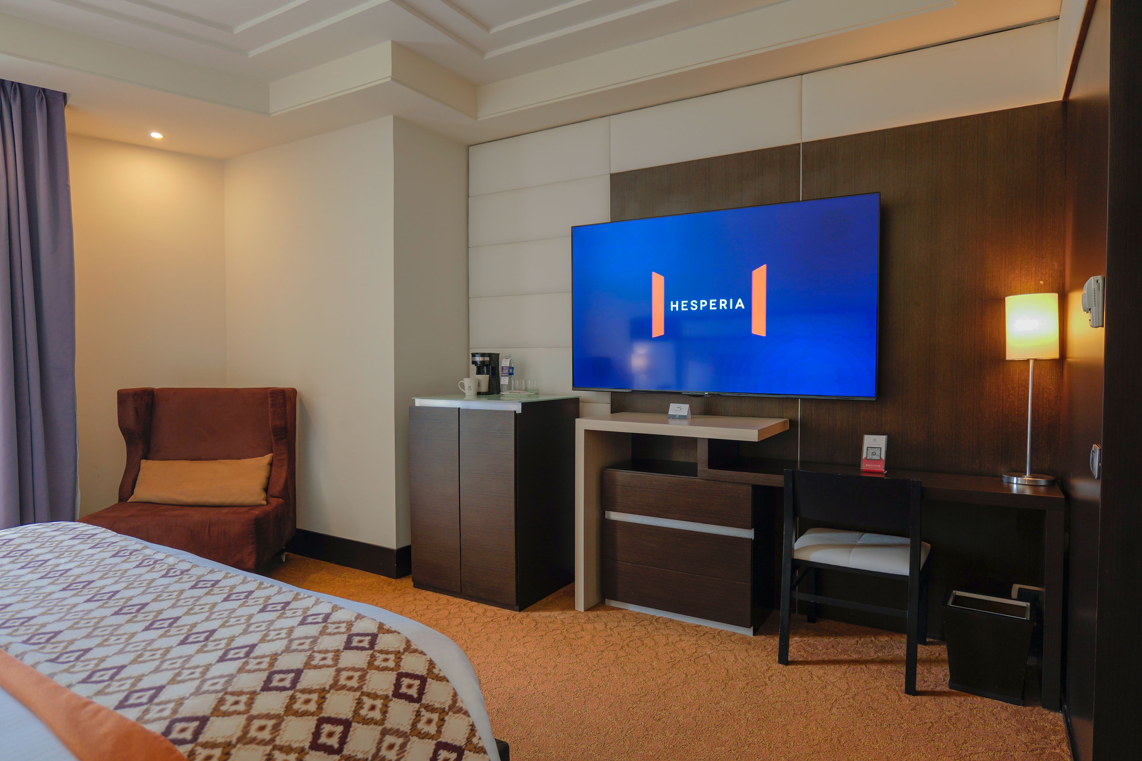 A hotel room with a bed, a desk, a television, and a chair.