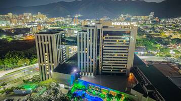 A hotel with multiple high-rise buildings, a swimming pool, and a view of a cityscape with mountains in the background.