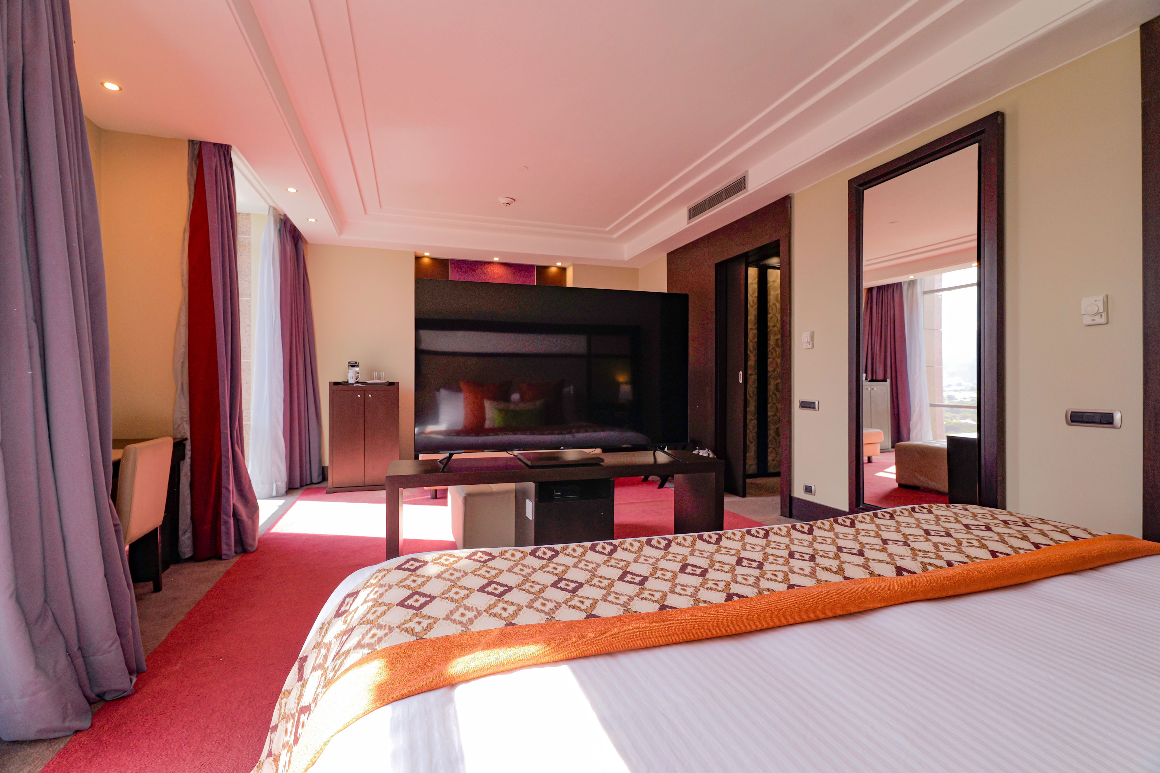Una habitación de hotel con una cama grande, un escritorio, un televisor y un armario.