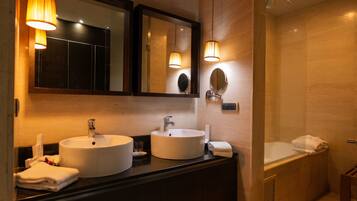 A modern bathroom with two sinks, a large mirror, and a bathtub.