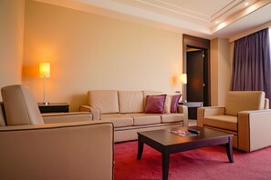 A hotel room with a beige sofa, a matching armchair, a coffee table, and two floor lamps. - Hotel Hesperia de Valencia (Naguanagua)